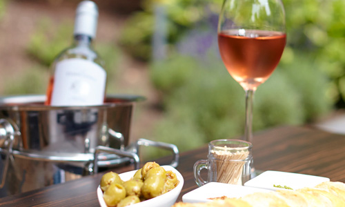 Een tafel met een hapje en een gekoelde fles wijn die te bestellen zijn in ons restaurant in Gelderland.  
